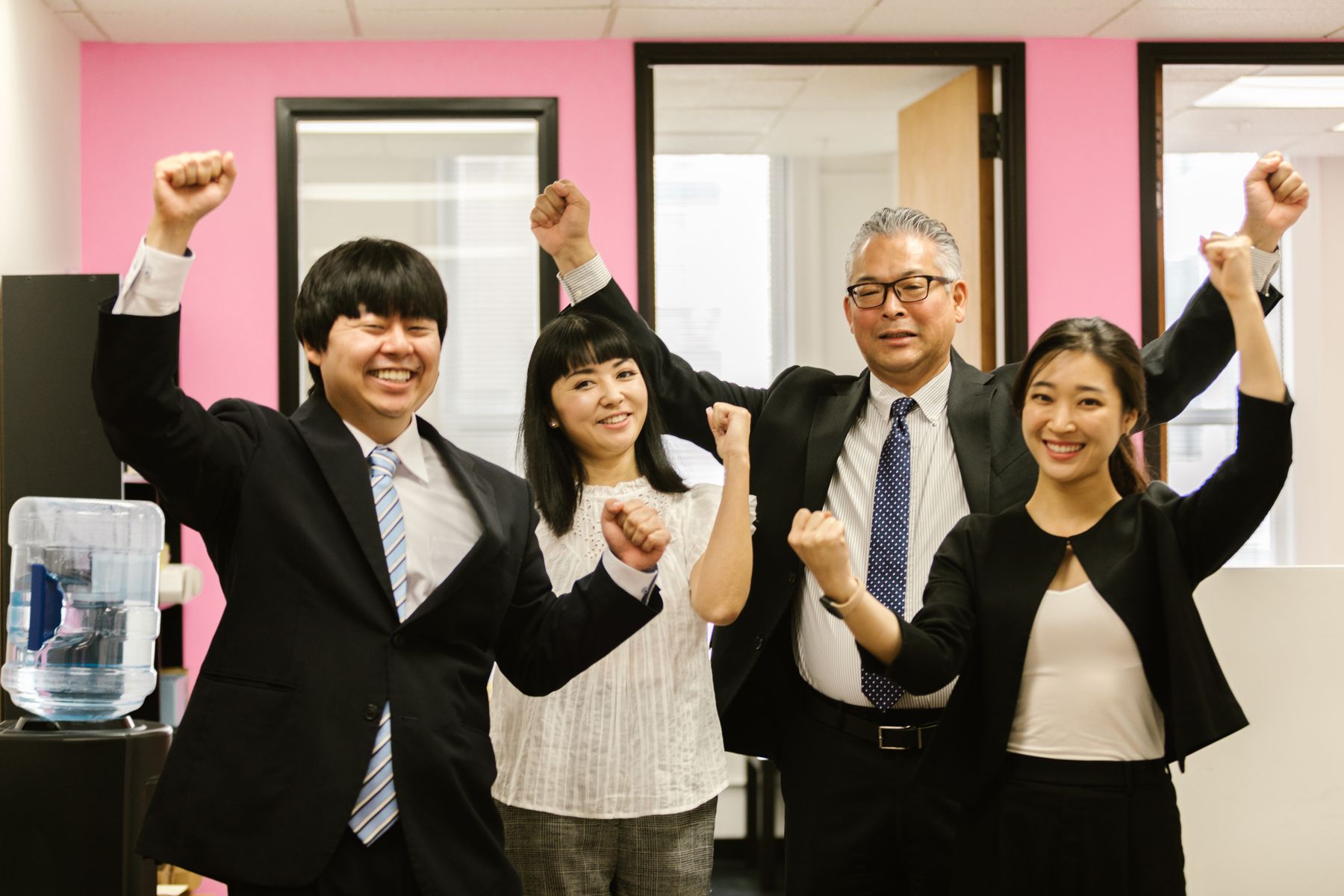 明るい未来に向けて笑顔で手を上げる日本人チームのイメージ写真